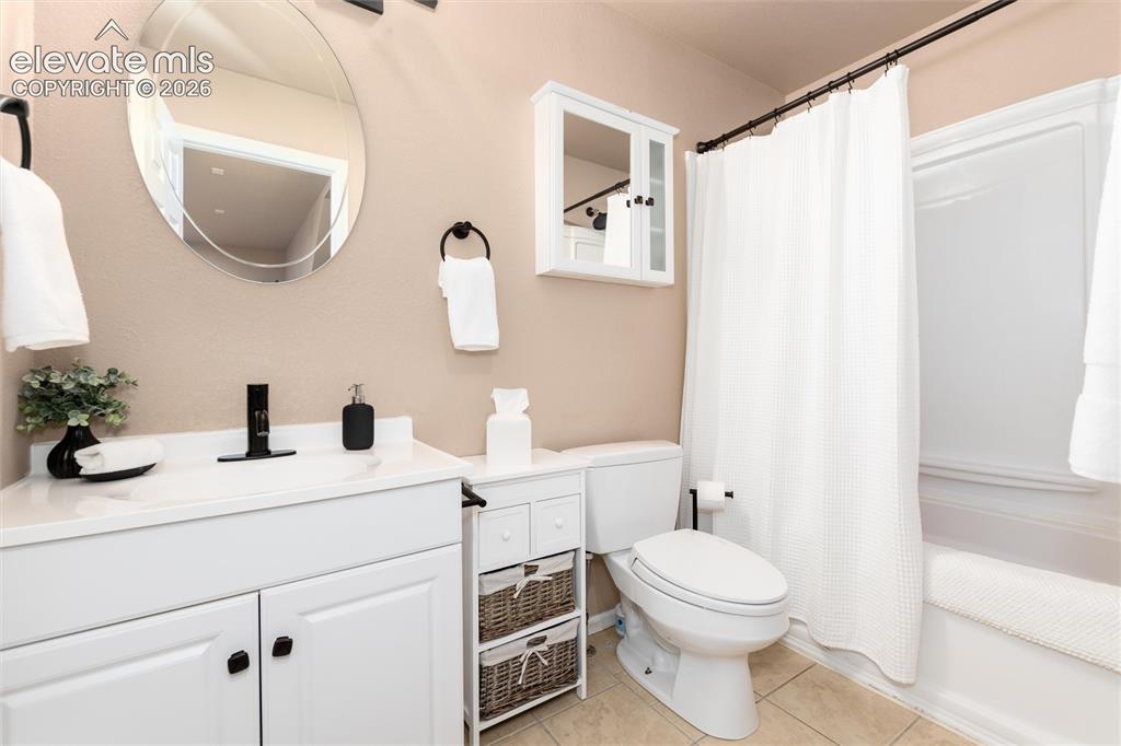 12730 Bridle Bit Road Colorado Springs, CO 80908 - Photo 39 of 50 Bathroom featuring a white vanity with integrated sink, black single-handle faucet, oval wall-mounted mirror, white medicine cabinet, and a shower-tub combination with white enclosure