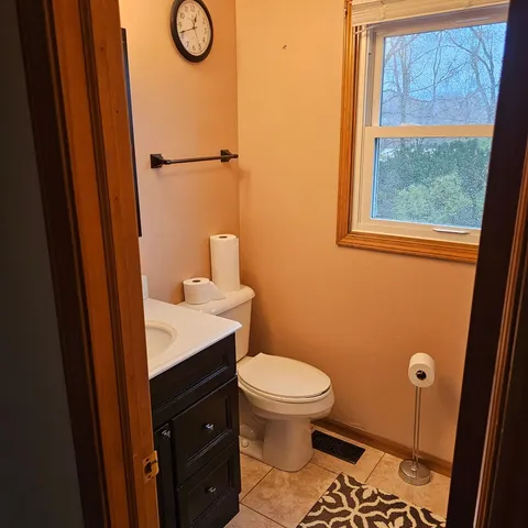 a bathroom with a sink a toilet a window and vanity