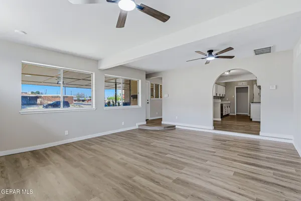 a view of an empty room with window and wooden floor