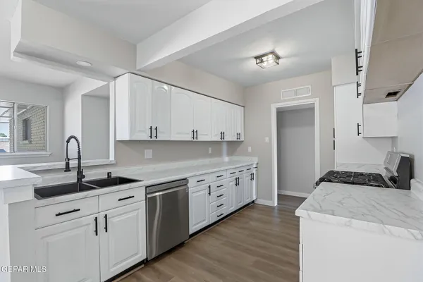 a kitchen with granite countertop a sink a stove and cabinets