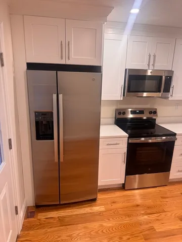 a kitchen with stainless steel appliances a refrigerator a stove and white cabinets