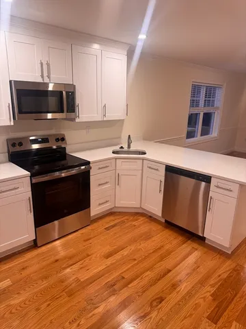 a kitchen with stainless steel appliances granite countertop a stove a sink dishwasher and a microwave oven with wooden floor