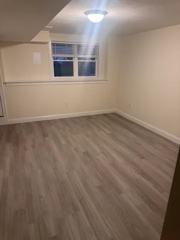 a view of an empty room with wooden floor and cabinet
