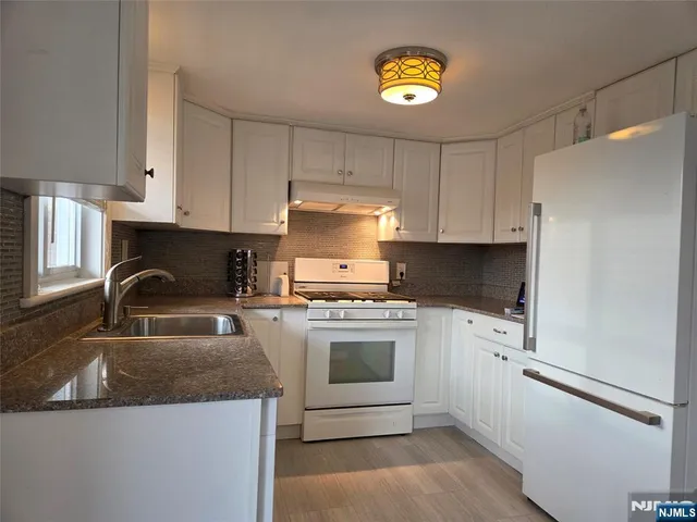 a kitchen with granite countertop a stove sink and refrigerator