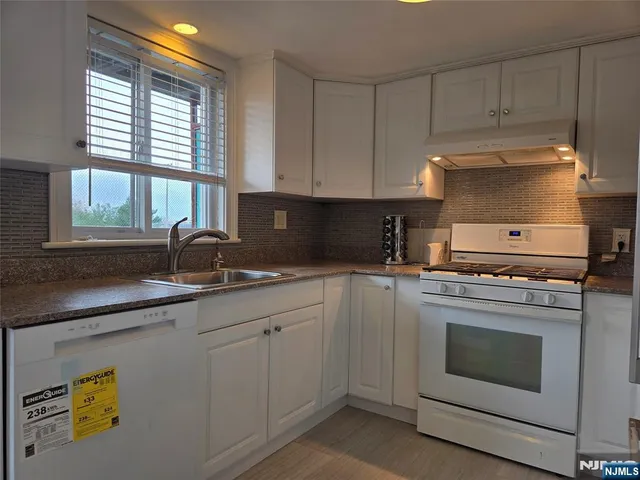 a kitchen with granite countertop white cabinets and white stainless steel appliances