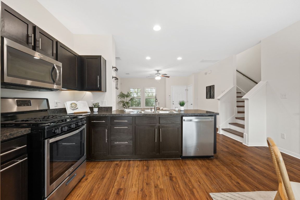 4517 Truth Way, Unit 412 Austin, TX 78725 - Photo 13 of 25 a kitchen with stainless steel appliances granite countertop wooden cabinets a stove top oven a sink and dishwasher