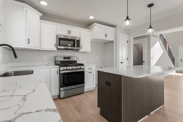 a kitchen with stainless steel appliances granite countertop a stove a sink and a microwave