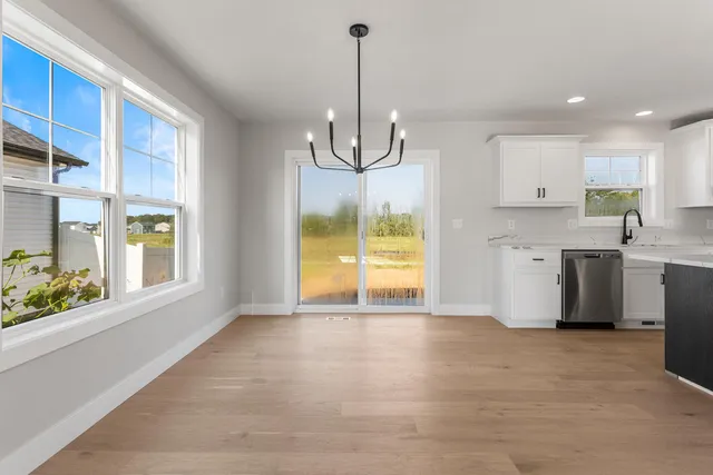a view of an empty room with a window and kitchen view