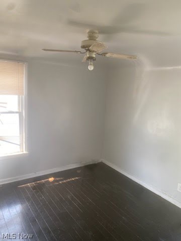 Unfurnished room with ceiling fan and dark hardwood / wood-style flooring