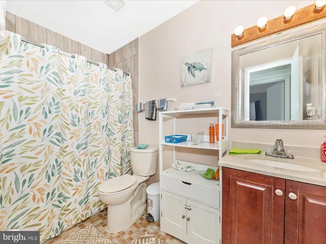 a view of a house with brick walls plants and large tree