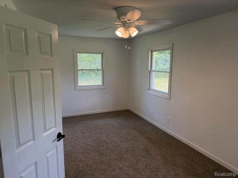 3515 Morton Road Stockbridge, MI 49285 - Photo 19 of 31 Carpeted room with white walls, two double-hung windows, and a ceiling fan with integrated lighting