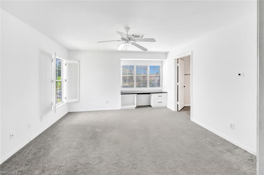 3520 Windjammer Circle, Unit 102 Naples, FL 34112 - Photo 15 of 26 an empty room with chandelier fan and windows