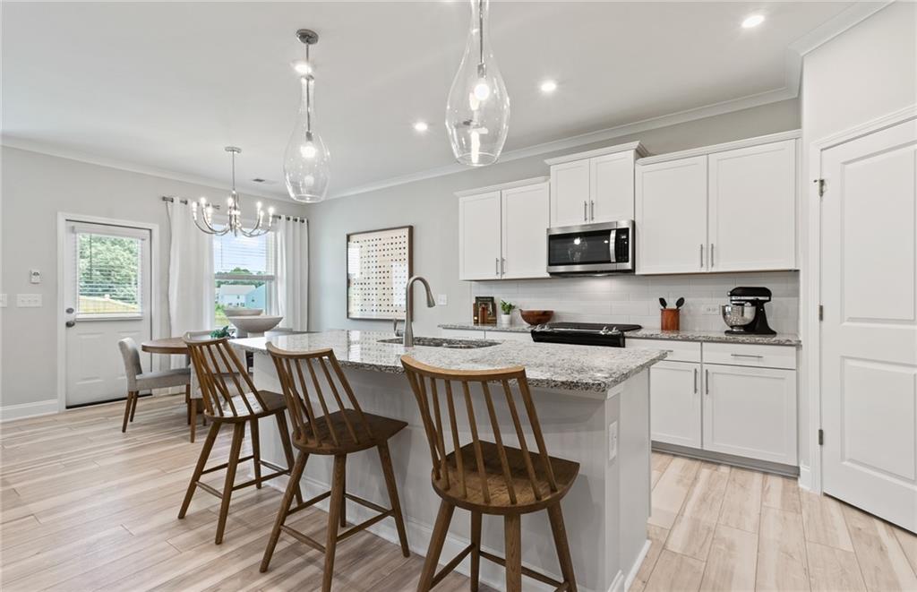 1647 Tide Ml Road Cumming, GA 30040 - Photo 8 of 21 a kitchen with stainless steel appliances granite countertop a stove top oven a sink dishwasher a dining table and chairs with wooden floor