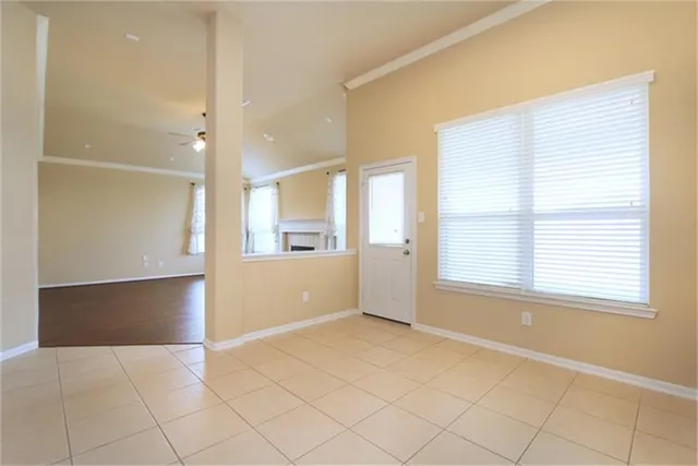 a view of an empty room with window and a kitchen