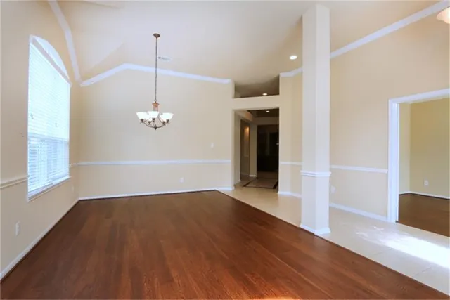 a view of empty room with wooden floor and kitchen view