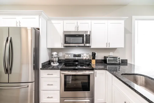 a kitchen with refrigerator a microwave a stove and cabinets