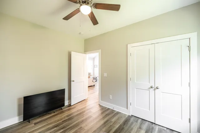 an empty room with wooden floor cabinet and a ceiling fan