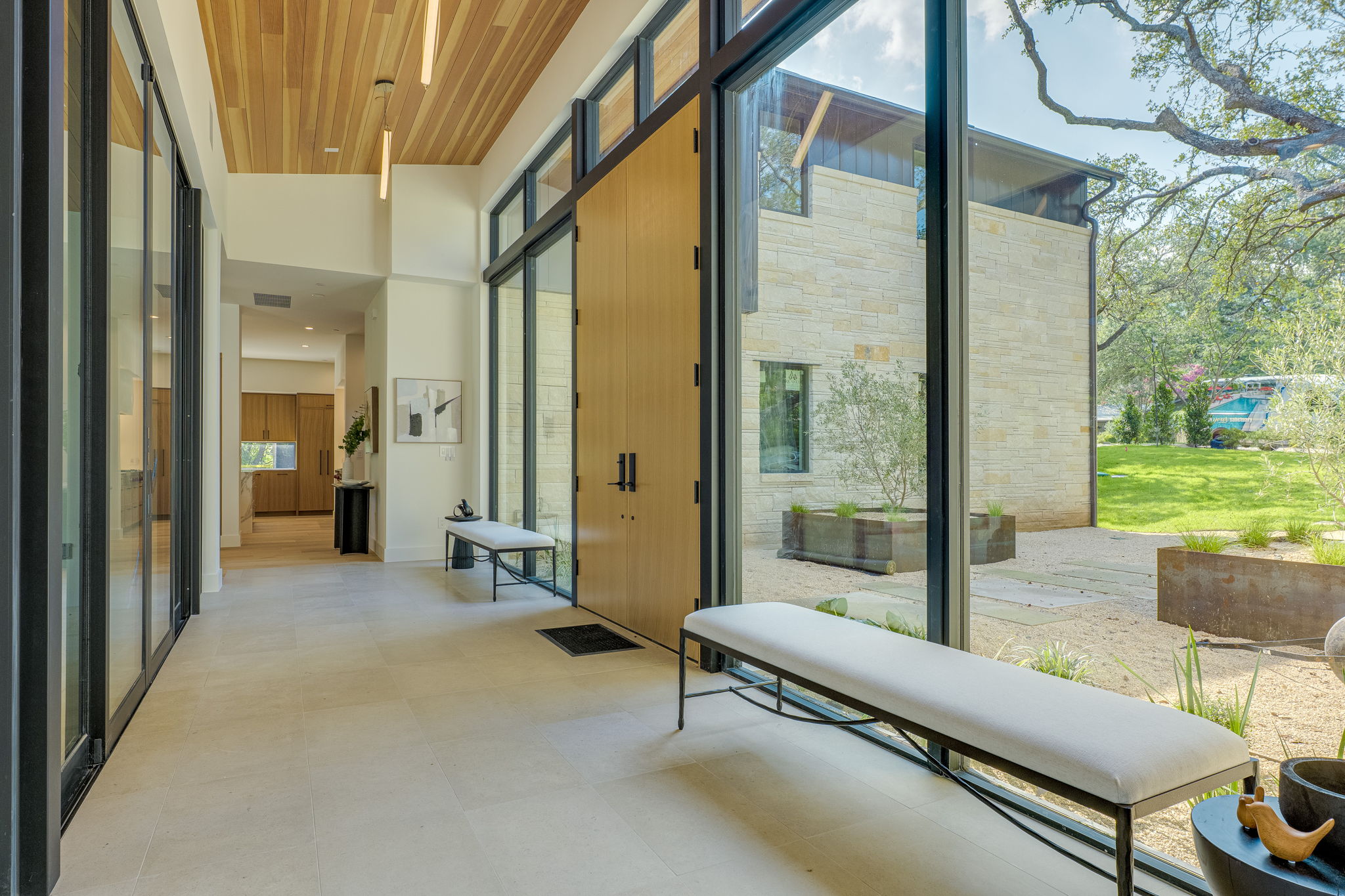 405 Honeycomb Ridge Austin, TX 78746 - Photo 4 of 15 A spacious entrance hall with tall ceilings features a wall of glass overlooking a meticulously landscaped yard.