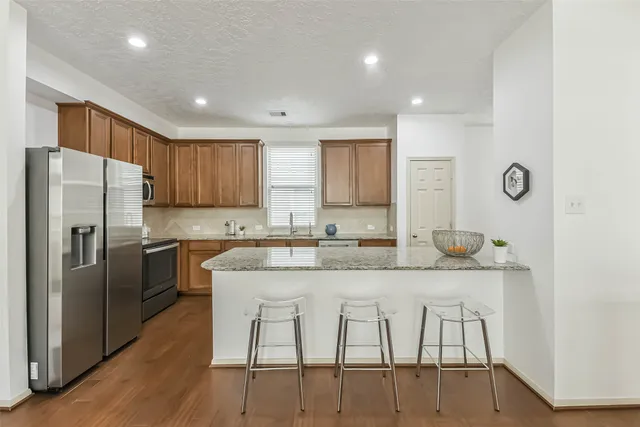 a kitchen with stainless steel appliances granite countertop a table chairs sink refrigerator and cabinets