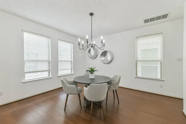 a dining room with wooden floor a chandelier a wooden table and chairs