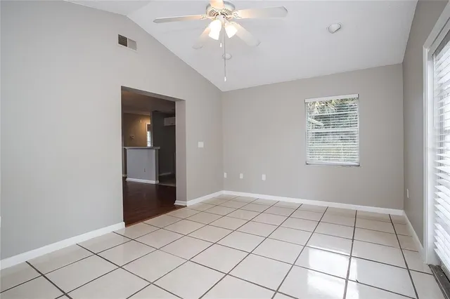a view of an empty room with window and chandelier fan
