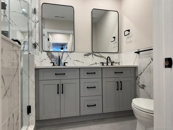 a bathroom with a double vanity sink mirror and toilet