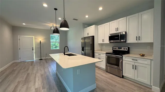 a kitchen with kitchen island a sink dishwasher a refrigerator and a stove with wooden floor