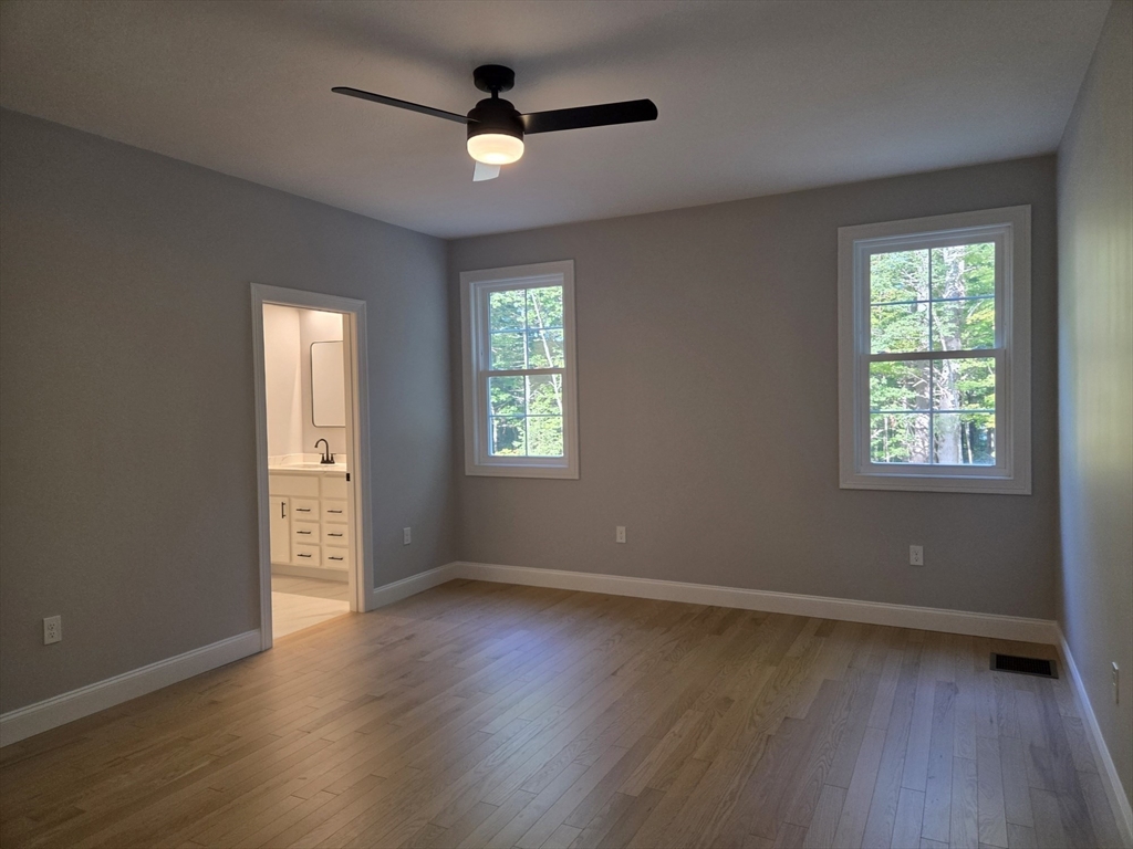 65 Adams Road Townsend, MA 01469 - Photo 10 of 18 an empty room with wooden floor fan and windows