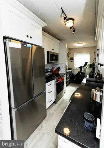 a kitchen with stainless steel appliances granite countertop a refrigerator a stove and a sink
