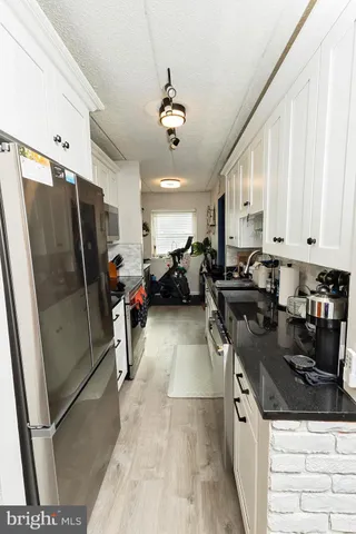 a kitchen with stainless steel appliances granite countertop a sink a stove a refrigerator a white cabinet with granite countertops and cabinets