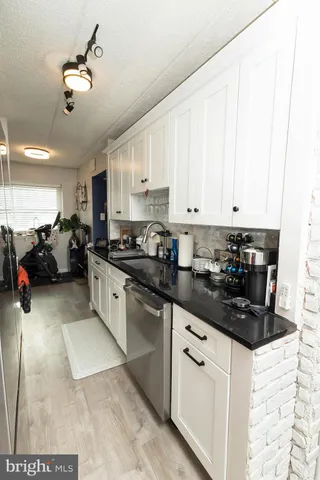 a kitchen with granite countertop white cabinets and black appliances