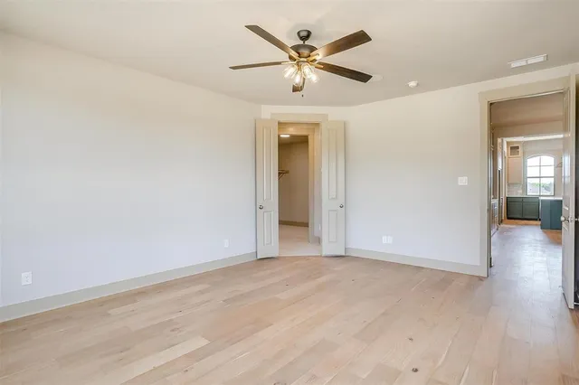 an empty room with wooden floor and a ceiling fan