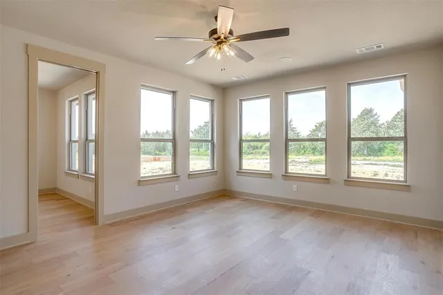 a view of an empty room with chandelier fan and a window