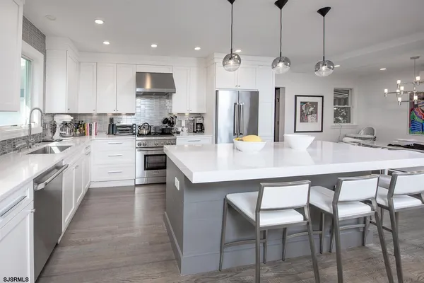 a kitchen with stainless steel appliances kitchen island granite countertop a sink a stove a dining table and chairs