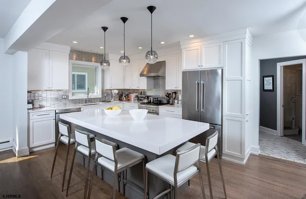 a kitchen with stainless steel appliances a dining table chairs and refrigerator