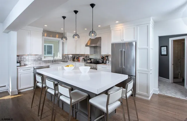a kitchen with stainless steel appliances a dining table chairs and refrigerator