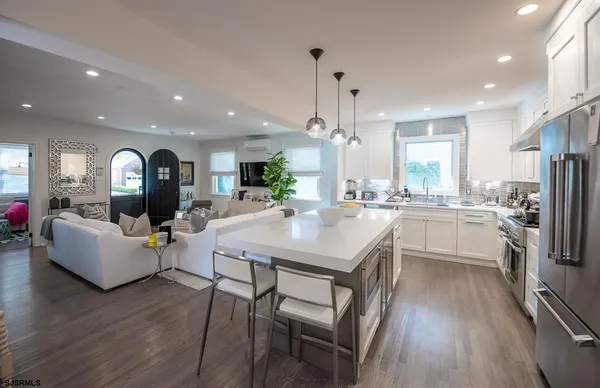 a large kitchen with sink a refrigerator a stove a dining table and chairs with wooden floor