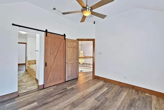 an empty room with wooden floor fan and windows