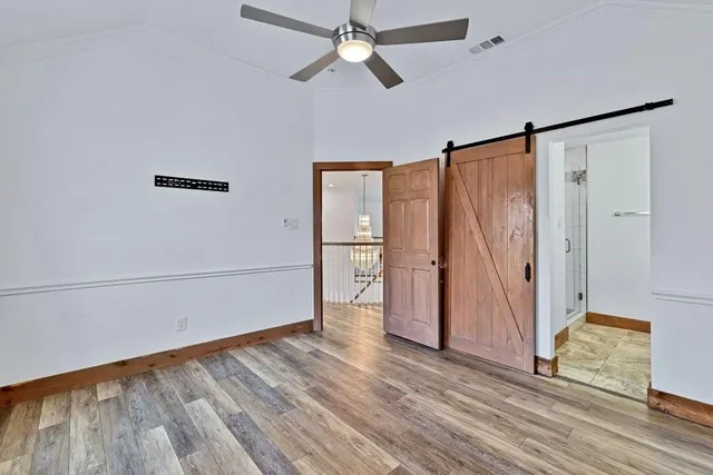 an empty room with wooden floor fan and windows