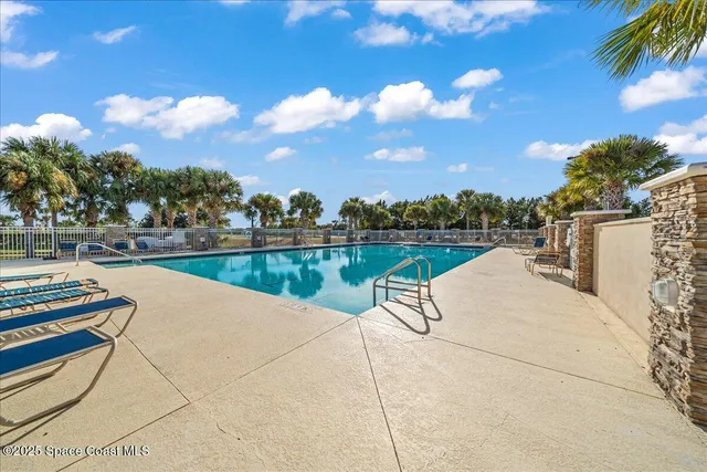 a view of swimming pool with lounge chair and trees in the background