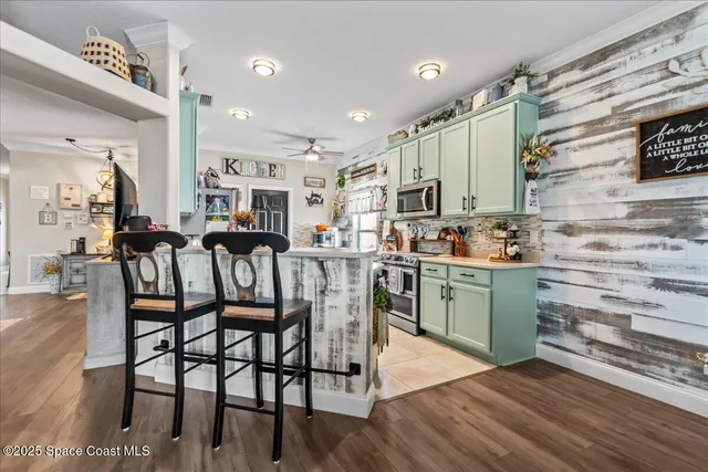 a kitchen with stainless steel appliances kitchen island granite countertop a table chairs sink and cabinets