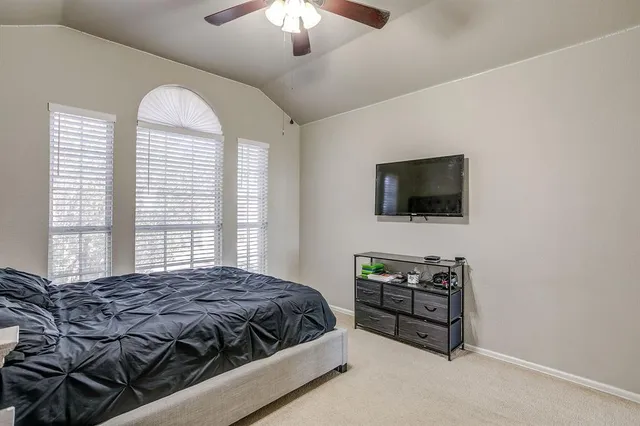 a spacious bedroom with a bed and a flat screen tv