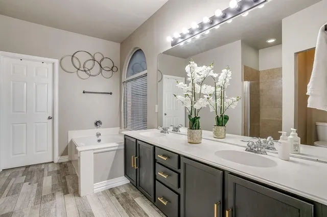 a bathroom with a double vanity sink mirror and bathtub