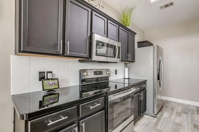 a kitchen with stainless steel appliances a stove a microwave a sink and cabinets