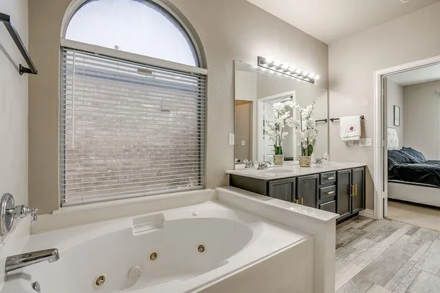 a bathroom with a tub a sink and a large mirror