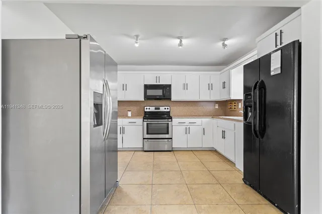 a view of a refrigerator in kitchen and an empty room