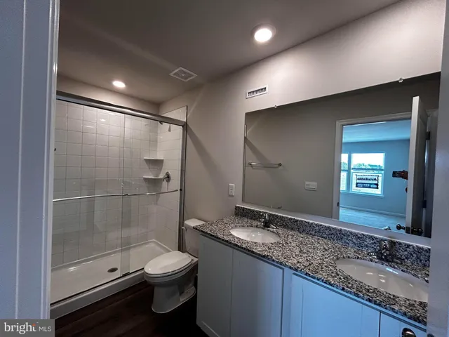 a bathroom with a granite countertop sink a toilet and shower