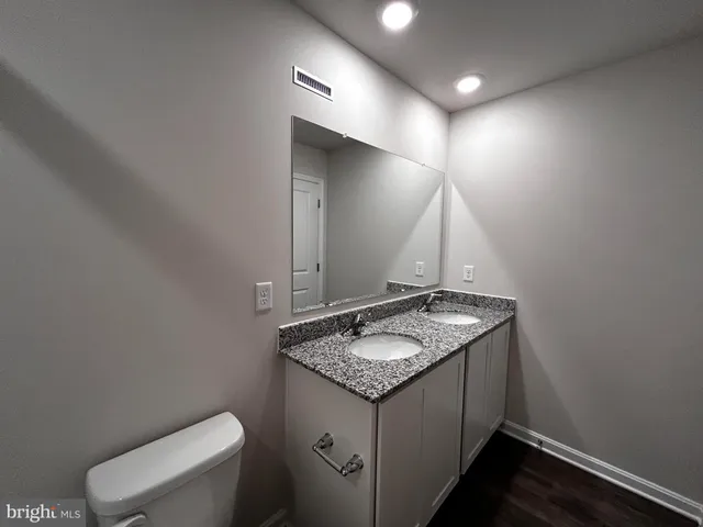 a bathroom with a granite countertop sink a toilet and a mirror