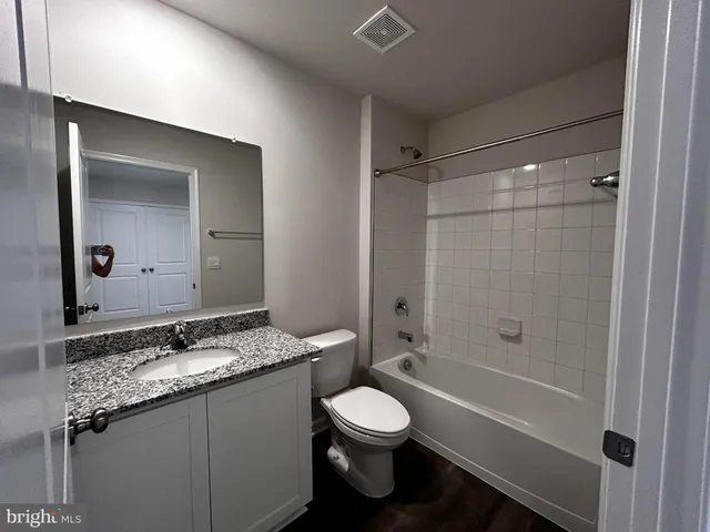 a bathroom with a granite countertop sink toilet mirror and bathtub