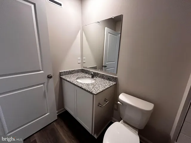 a bathroom with a granite countertop toilet and sink